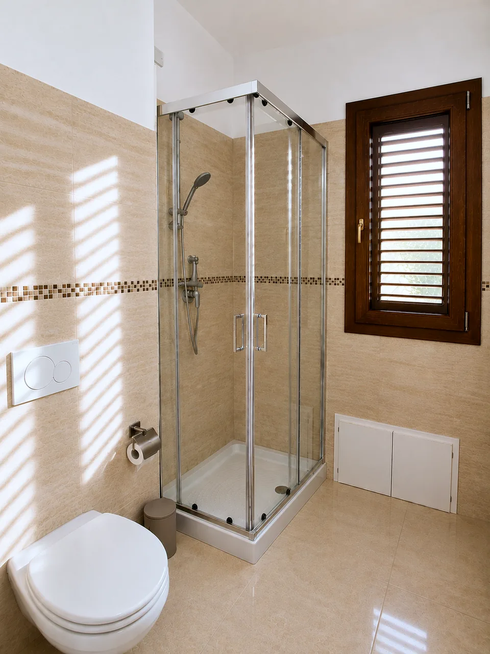 Corner shower with clear glass sliding doors and chrome fittings in the La Dolce Vita bathroom, beside the wall-hung toilet and shuttered wooden window