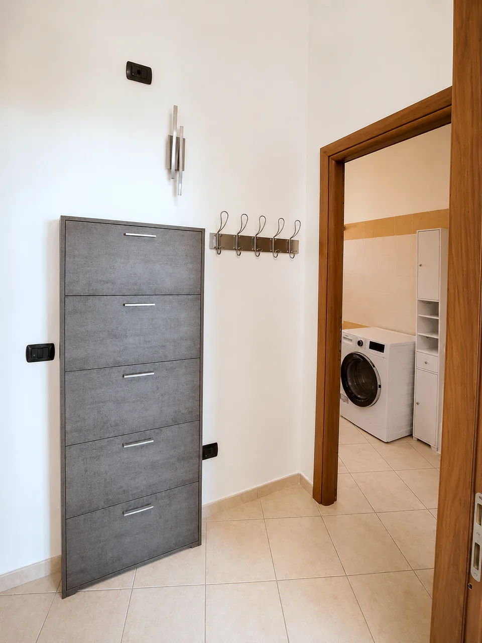 Entrance hall with grey shoe cupboard and coat hooks leading into the bathroom