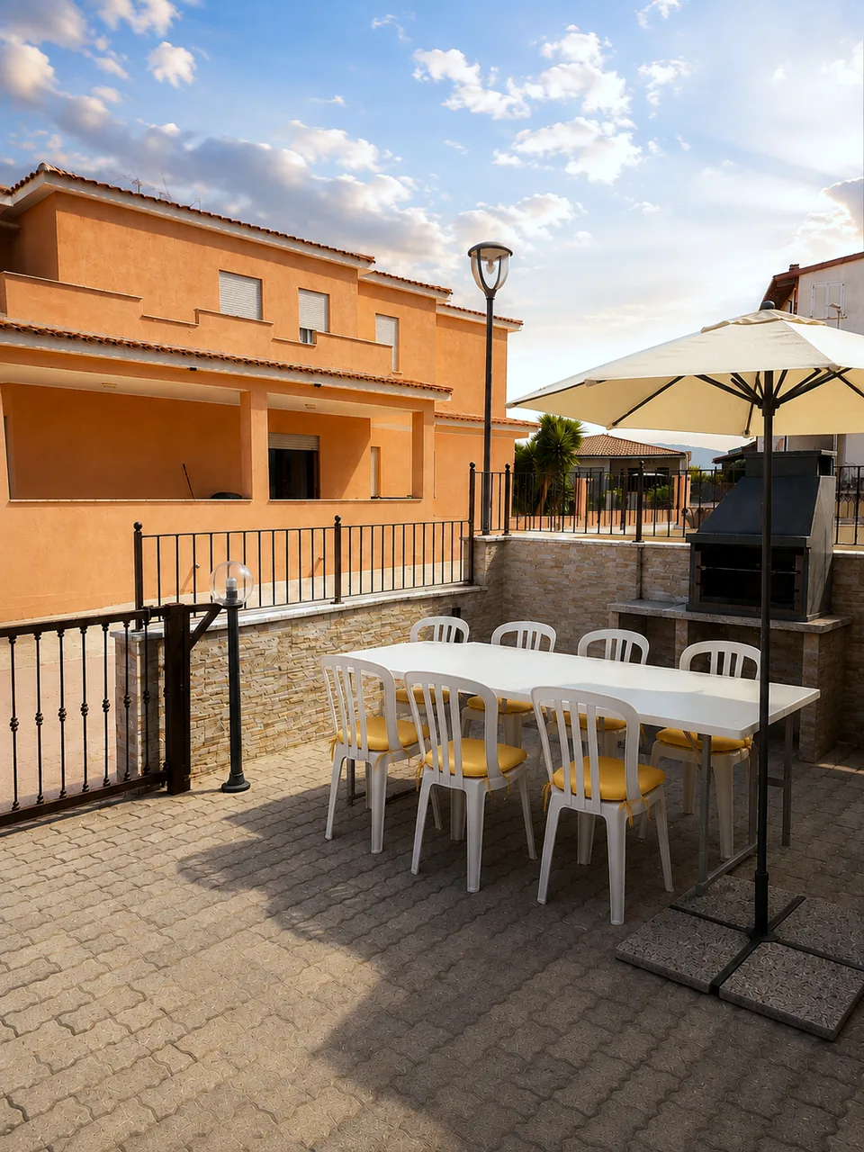 La Dolce Vita terrace at sunset with parasol shading the outdoor dining table and the barbecue beyond