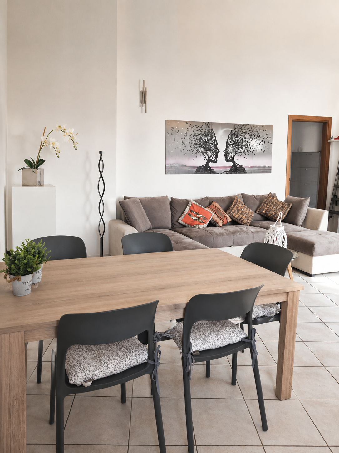 Dining table for six with orchid and artwork, looking through to the lounge