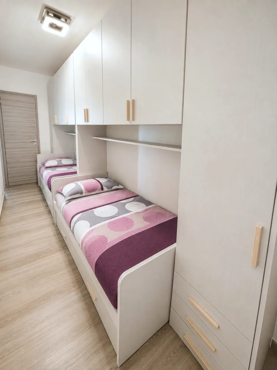 Second bedroom at Il Paradiso with two single beds, pink and grey patterned bedding and full-height ivory fitted wardrobes with pale ash handles