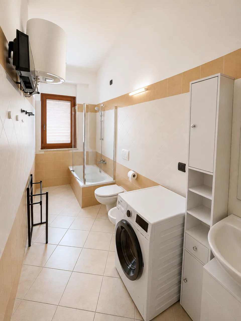 Bathroom with bathtub, toilet, bidet, washing machine and tall storage unit