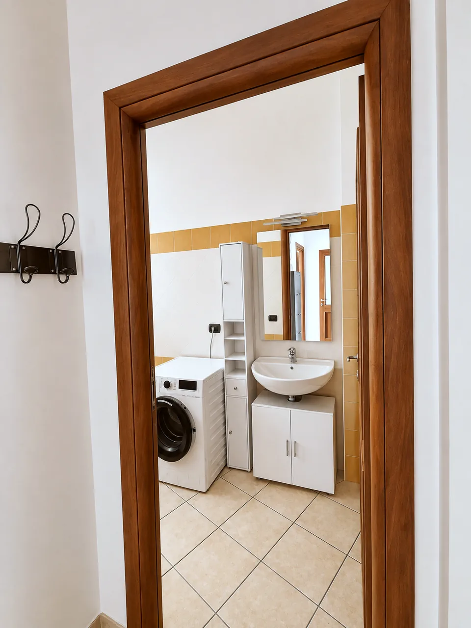 View from the hall through the bathroom door to the washbasin, vanity and washing machine