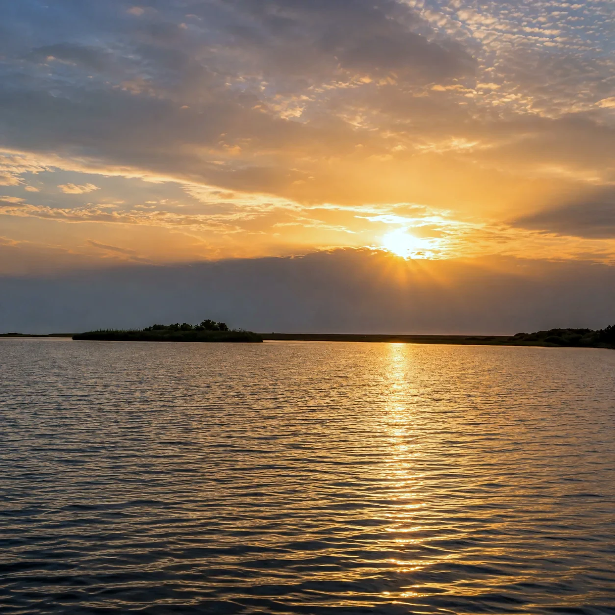 Le soleil se couchant sur la lagune et ses îlots de roseaux