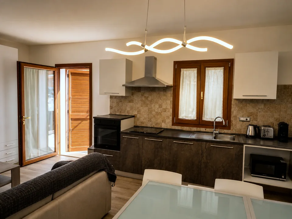 Fully equipped kitchen at Il Paradiso at dusk with dark wood cabinets, induction hob, oven, extractor hood, microwave and Nespresso machine