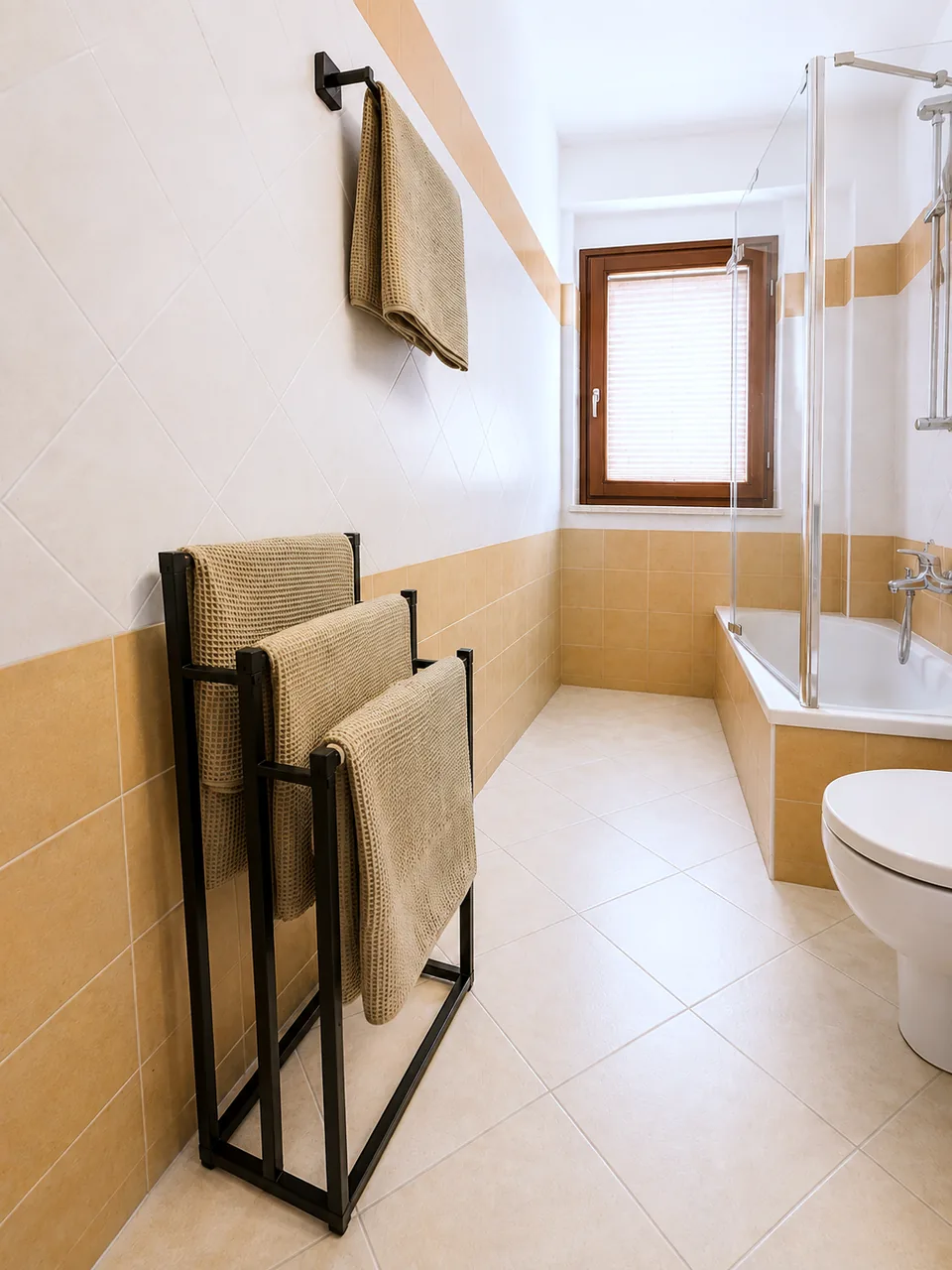 Fresh towels on the bathroom towel rack beside the bathtub and window