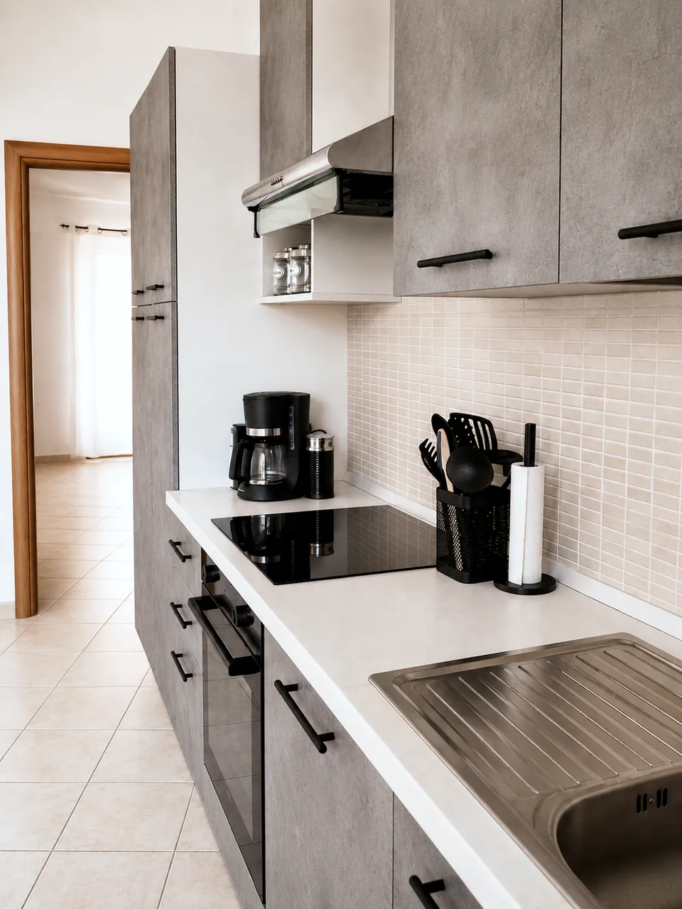 Kitchen worktop with extractor hood, hob and coffee machine looking through to the hall