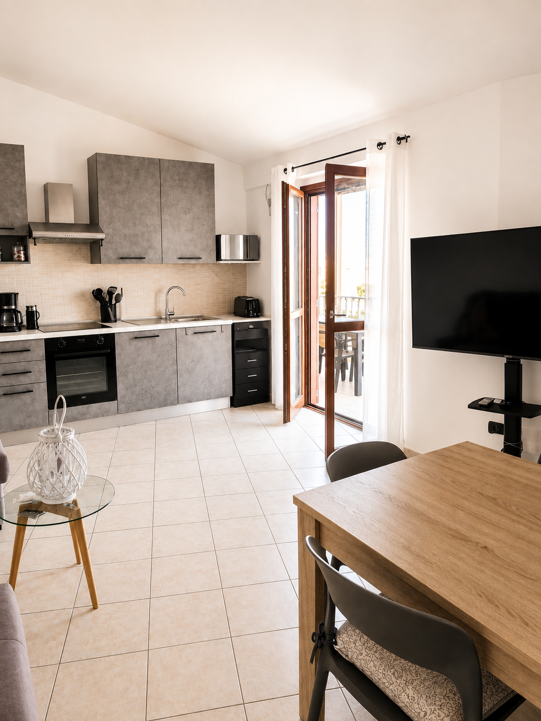 Open-plan kitchen with induction hob, oven, microwave and smart TV, opening onto the balcony