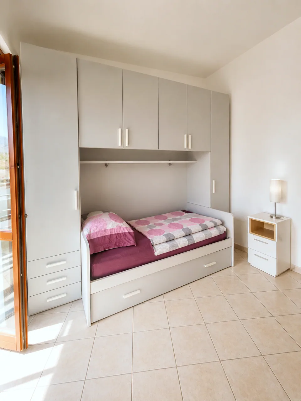 Second bedroom single bed with fitted wardrobe and overhead storage in bright daylight